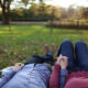 A couple holding hands and laying on the grass in a park